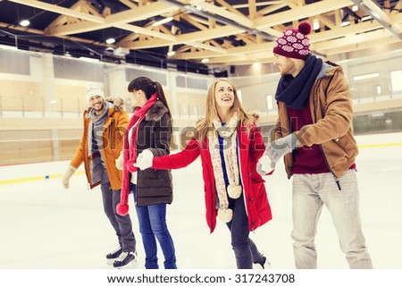 people, friendship, sport and leisure concept - happy friends on skating rink