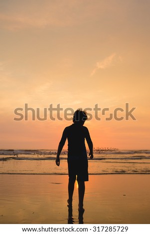Silhouette of a Boy Walking on the Beach