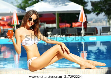 Young woman enjoying with cocktail at swimming pool