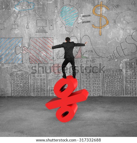 Businessman balancing on red percentage sign, with business concepts doodles wall.