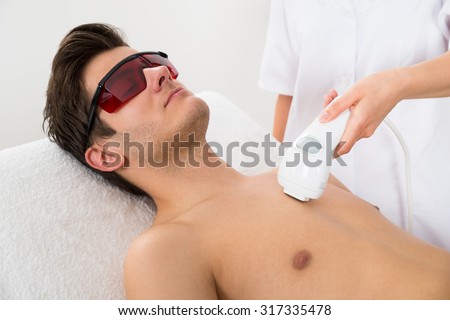 Close-up Of Female Worker Giving Man Laser Epilation On Chest In Salon Royalty-Free Stock Photo #317335478