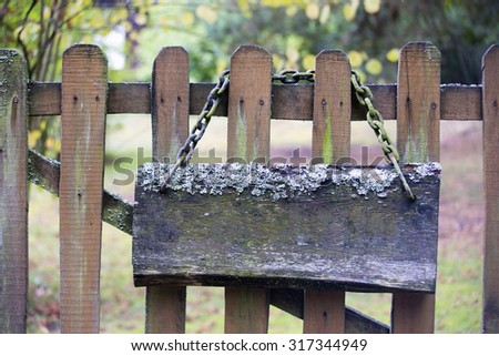 Old mossy signboard with chain on a wooden fence in summer