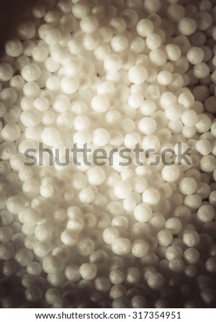 White pieces of foam plastic like snow balls. Volumetric background. Closeup. Toned.