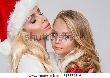 Christmas concept. Beautiful blonde mother with daughter dressed in a Santa Claus costume. Christmas mood and love of mother.