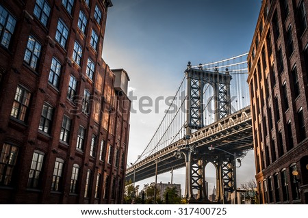 Manhattan bridge seen from a narrow alley enclosed by two brick buildings on a sunny day in summer Royalty-Free Stock Photo #317400725