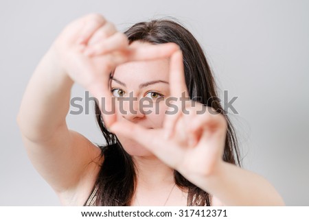 Portrait of a winking young woman making a frame sign with her hands