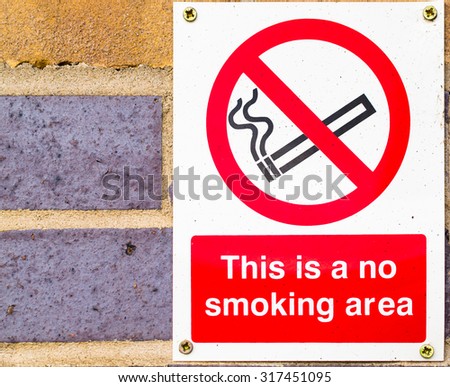 Single This is a No Smoking Area sign attached to an exterior brick wall reminds commuters not to smoke at a Witham Train station in the Summer of August 2015