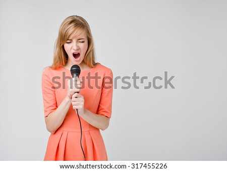 Beautiful young woman singing into a microphone in dress, showing expressions and emotions