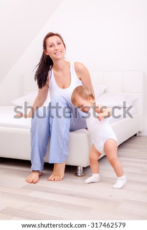mom watching little daughter making first steps