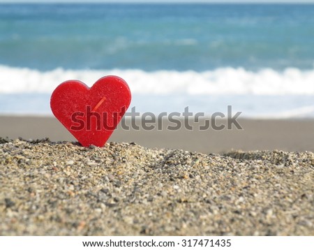 Red heart on white sand beach