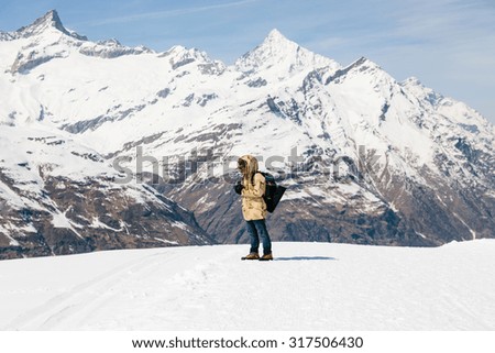 A man taking a photo with vintage film camera on the snow in the background of snow mountain.
