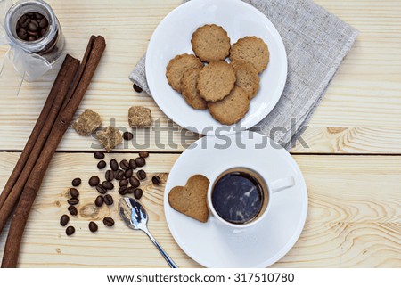Ginger biscuits, cinnamon, a cup of hot coffee. Walnuts, hazelnuts on a wooden background