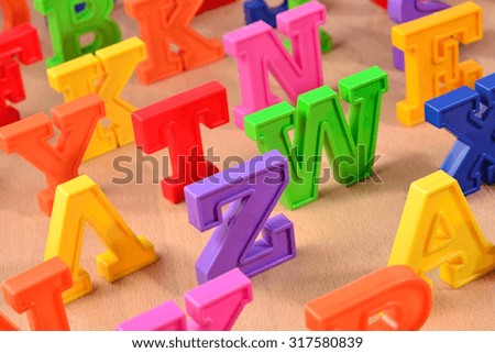 Plastic colorful alphabet letters close up on a wooden background