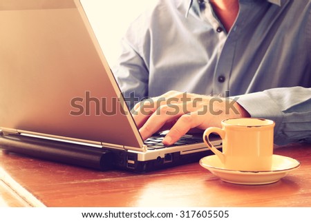 close up image of man using laptop next to cup of coffee. retro style image. selective focus
