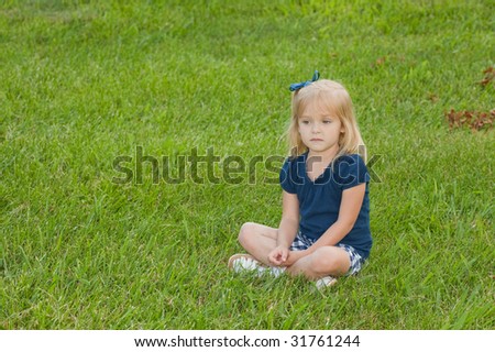 blond girl sitting alone in the grass