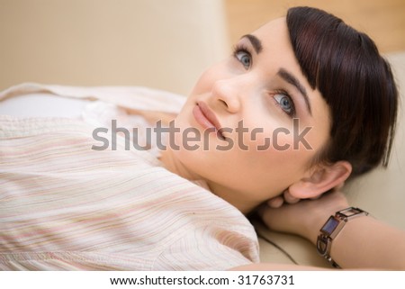 Portrait of young woman resting on a couch at home, smiling.