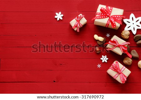Festive red Christmas card background with copyspace and a holiday border of decorative Xmas gifts, snowflake ornaments and assorted fresh whole nuts
