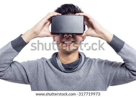 Man wearing virtual reality goggles watching movies or playing video games.  He is isolated on a white background.  The vr headset design is generic and no logos.
