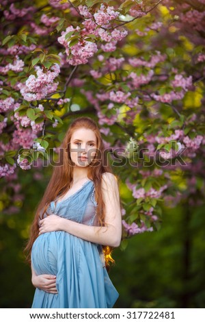 Young beautiful pregnant girl with long brown hair in blue dress