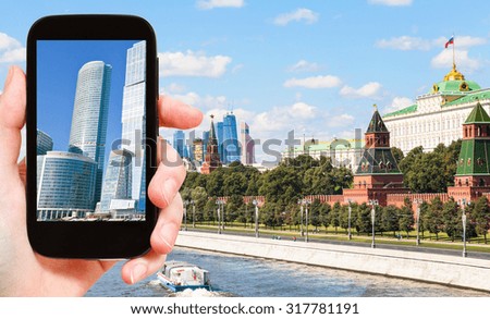 travel concept - tourist photographs picture of Moscow City towers on smartphone