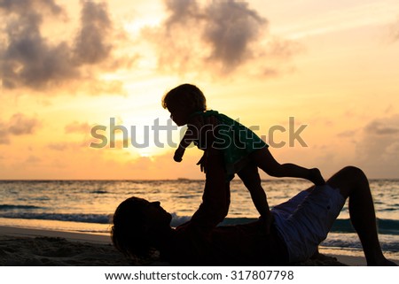 Father and little daughter silhouettes play at sunset
