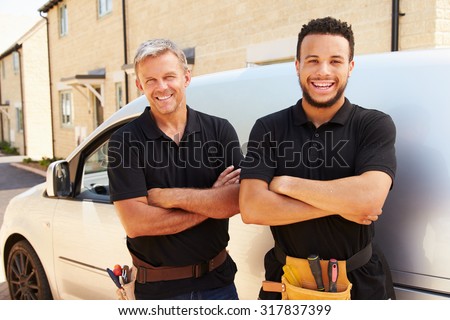 Portrait of a young and a middle aged tradesman by their van Royalty-Free Stock Photo #317837399