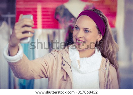 Smiling woman taking selfies at shopping mall