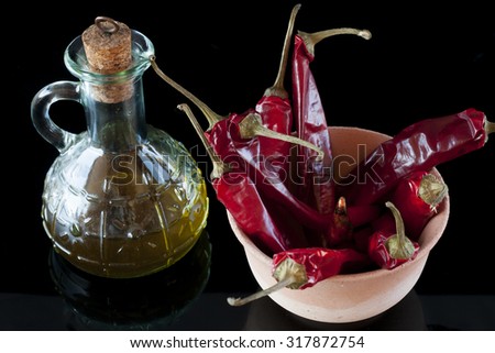 red chillies and olive oil in a jar of clay on a black background