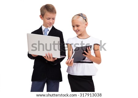 schoolboy and schoolgirl with a laptop with a tablet on a white background smiling, picture with depth of field and artistic blur
