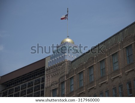 Prominent downtown building in San Antonio Texas with a golden dome flying the state flag