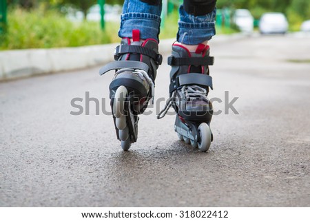 Closeup  inline skates  on the legs over the wet asfalt.