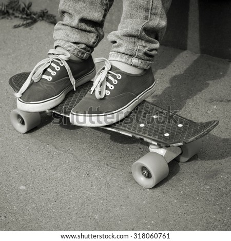 Teenager feet in jeans and gumshoes on a skateboard