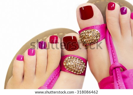 Pedicure with different colors of paint on a woman's feet in pink sandals on a white background. Royalty-Free Stock Photo #318086462
