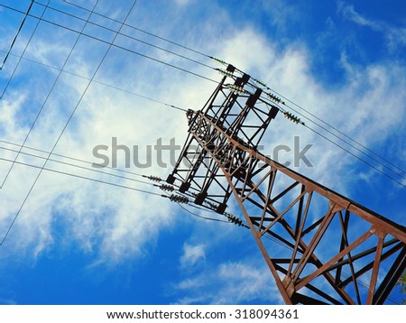 Upward view on power lines on a background of blue sky with clouds