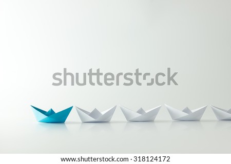 Leadership concept with blue paper ship leading among white Royalty-Free Stock Photo #318124172