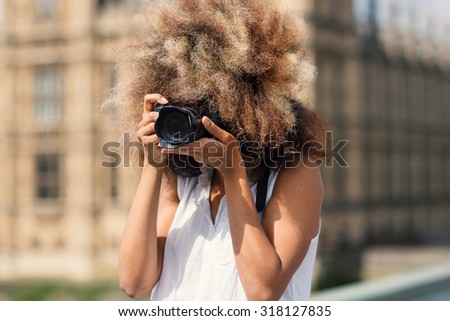 Young woman with camera taking photos in London on Westminster bridge on a sunny day.
