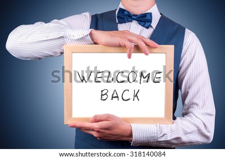 a man with a sign in his hand with the inscription welcome back