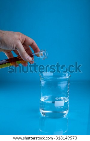 Pouring a yellow liquid into a beaker of water.