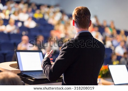 Speaker at Business Conference with Public Presentations. Audience at the conference hall. Entrepreneurship club. Rear view. Horisontal composition. Background blur. Royalty-Free Stock Photo #318208019