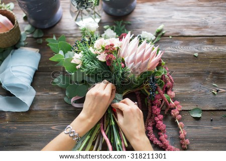 Florist at work: pretty young blond woman making fashion modern bouquet of different flowers Royalty-Free Stock Photo #318211301
