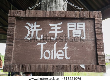 A sign outside public toilet in thailand with writing in English and thai.
