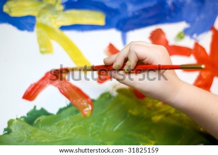 Close up of child hand drawing colorful picture with brush and paints