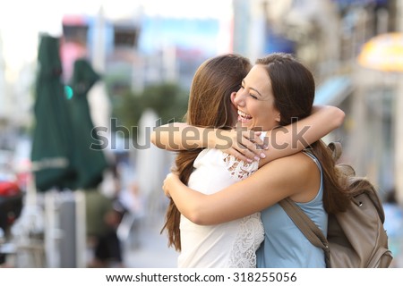 Happy meeting of two friends hugging in the street Royalty-Free Stock Photo #318255056