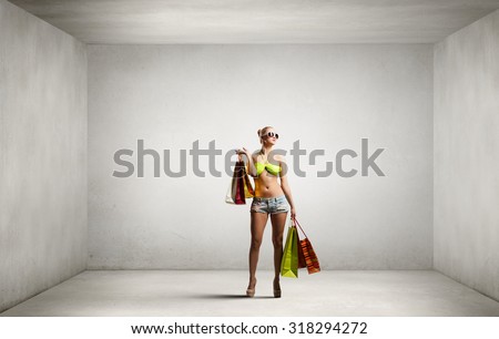Young pretty woman in bikini and shorts with shopping bags