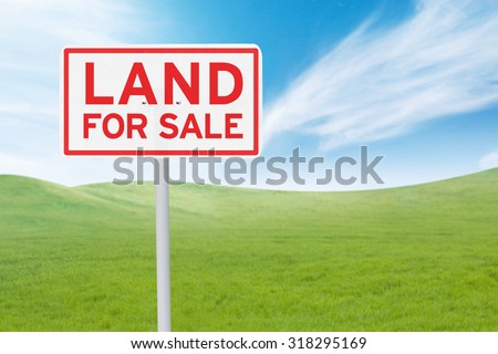 Real estate concept. Land For Sale signboard on the meadow under clear sky