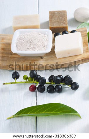 cosmetic clay, soaps, henna blocks, sponge and moisturizer on white wood table 