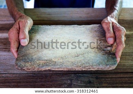 The old man holding a piece of wood