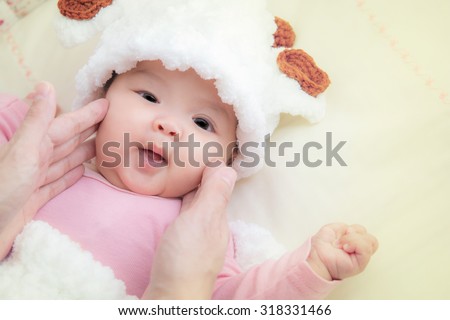 Cute asian Baby in baby cocoon or sleeping bag with her mather hand touch on face ,Vintage and soft picture style