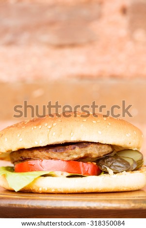 Classic homemade hamburger with onion rings and french fries on a wooden plate. Juicy homemade food. Vertical, cropped