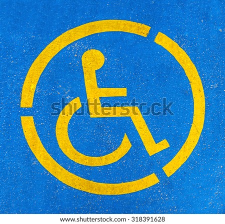Blue and yellow handicap parking sign on asphalt, persons with disabilities